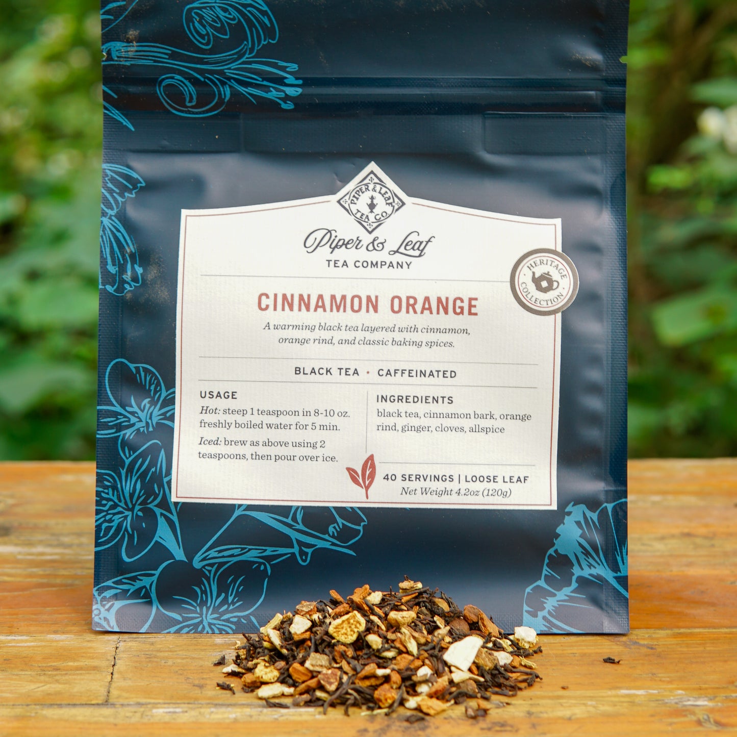 A package of Piper and Leaf Tea Co. Cinnamon Orange 40 Serving Loose Leaf Tea is displayed on a wooden surface, with a small pile of loose tea leaves and aromatic spices arranged in front.