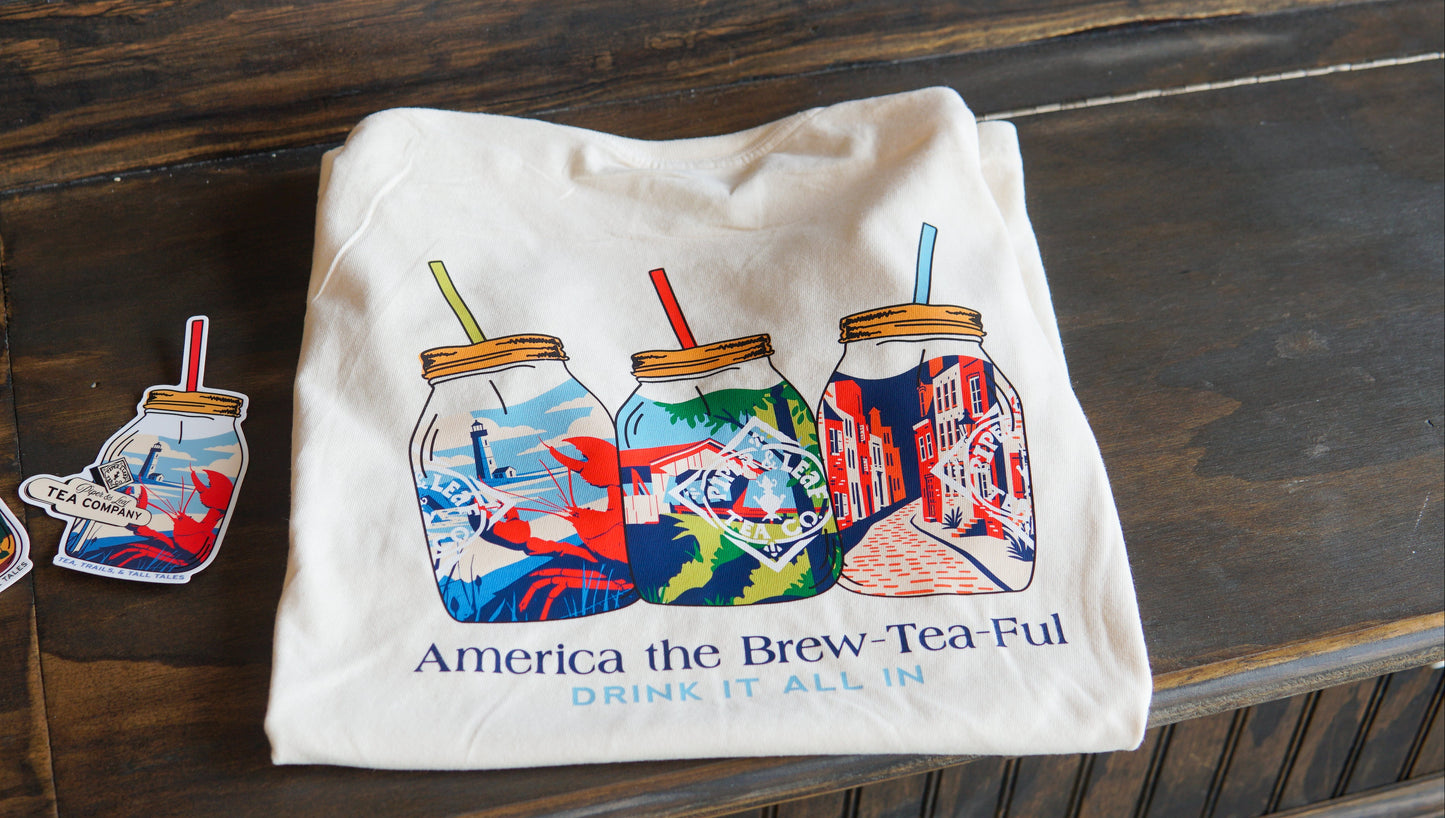 The Piper and Leaf Tea Co. Nor'Easter Adventure T-shirt is a white tee with three illustrated mason jars in American-themed designs and the phrase "America the Brew-Tea-Ful, Drink It All In" printed below.