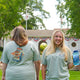 Two women are outdoors; one smiles at the camera holding a blue water bottle, while the other displays the back of her Piper and Leaf Tea Co. 